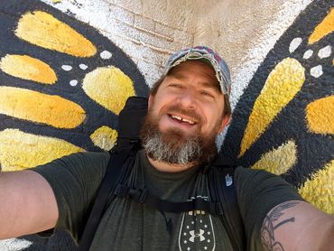 Matty posing for a selfie in front of painted monarch butterfly wings in West Texas.