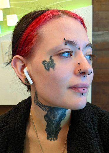 Profile of an attractive young woman with red-dyed streaks in her brown hair, tattoos and piercings 