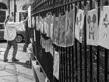 Man painting with works displayed in the French Quarter, New Orleans