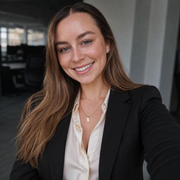 Smiling woman in business attire taking a selfie.