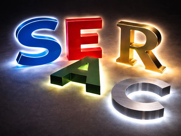 Colorful illuminated letters S, E, R, A, and C on a dark surface.