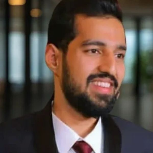 Smiling man in a suit and tie in a modern office.