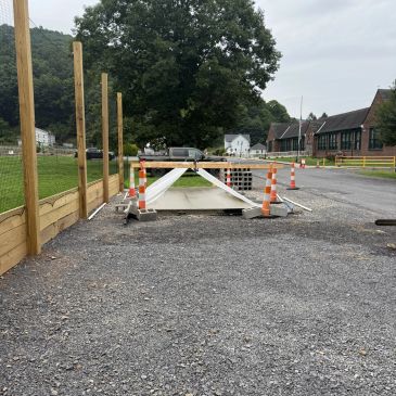 Construction area with traffic cones and barricades around a covered trench.