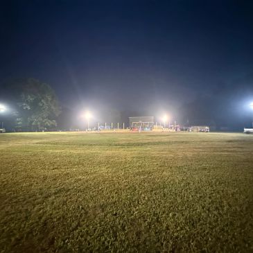 Empty sports field illuminated by bright lights at night.