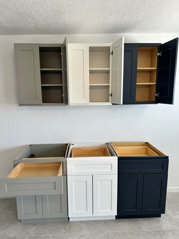 Three-tone kitchen cabinets with open doors and drawers.