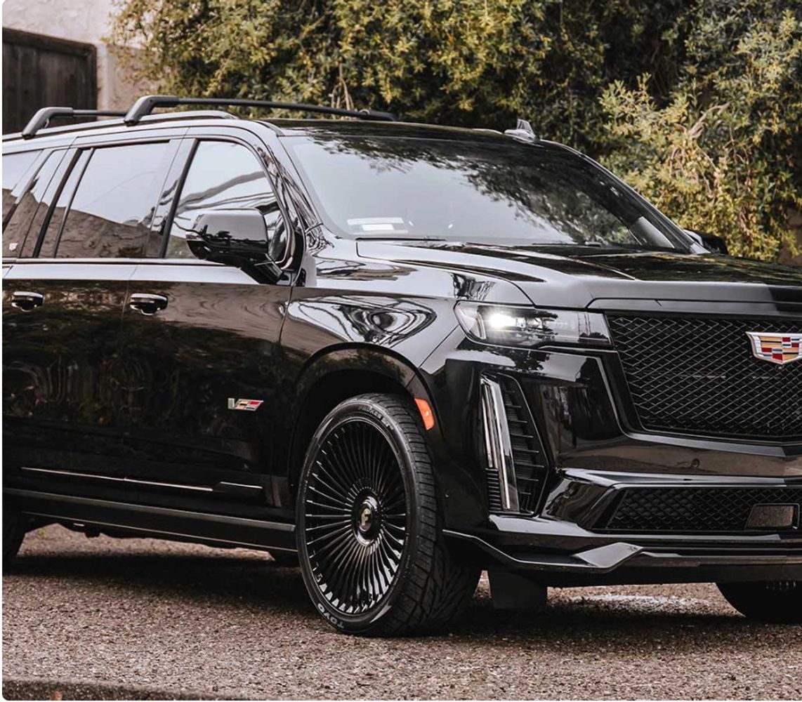 Sleek black Cadillac SUV with modern design and stylish rims parked outdoors.