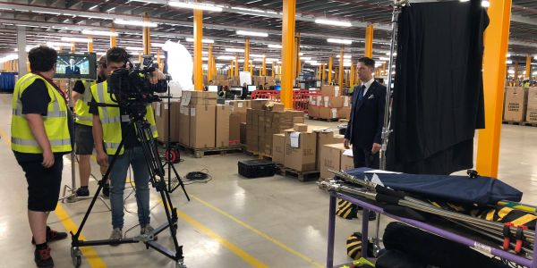 Film crew shooting in a warehouse with a suited man.