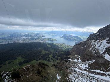 A scenic mountain view overlooking a lake with cloudy skies.