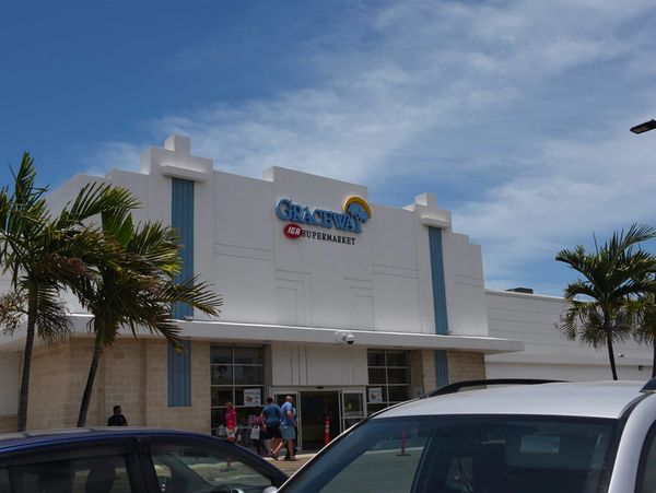 Front view of Graceway IGA Supermarket with parked cars and palm trees.