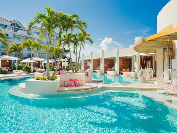 Luxurious resort pool with palm trees and cabanas.
