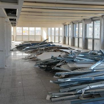 An empty room with construction debris and metal scraps piled on the floor after a strip-out.