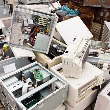 Pile of discarded old computer hardware and printers outdoors.