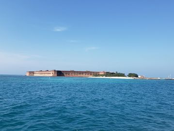 Historic fort on a small island surrounded by blue ocean under clear sky.
