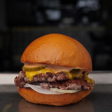 Classic cheeseburger with pickles and onions on a soft bun.