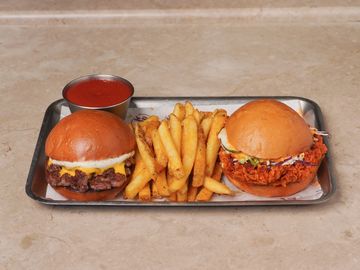 Two gourmet sandwiches with seasoned fries and ketchup on a metal tray.