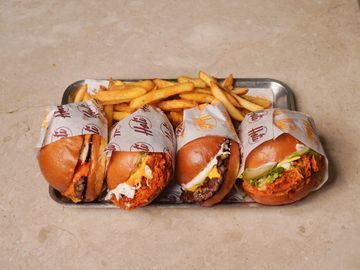 Four sandwiches and fries on a metal tray.
