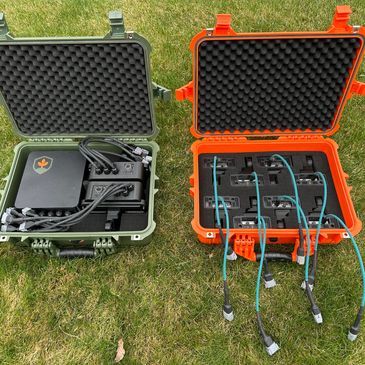 Two rugged cases with electronic equipment and cables on grass.