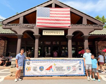 Two men holding a banner in front of Chappaqua building.