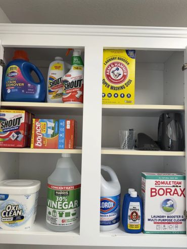 Clean and organized laundry cabinet with various cleaning supplies.
