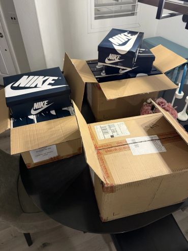 Multiple Nike shoe boxes packed in cardboard boxes on a table.