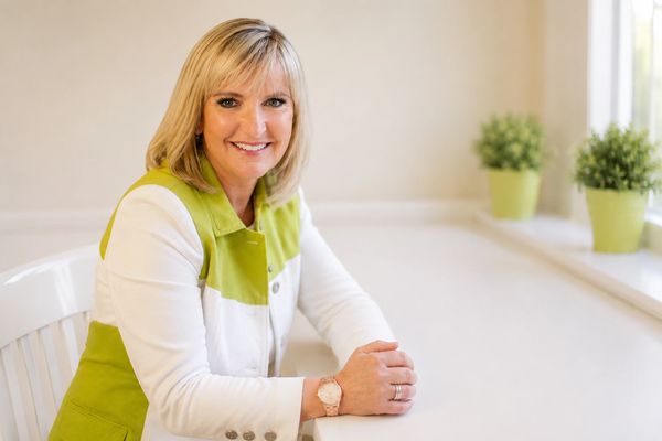 Smiling woman with blonde hair in a bright, cozy room.