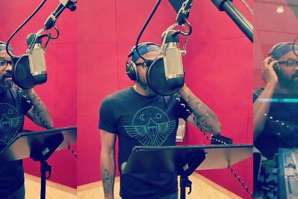 Man recording vocals in a studio with a red backdrop.