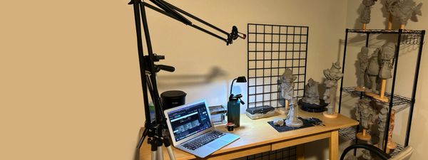 Workspace with laptop and sculpting tools on a wooden table.