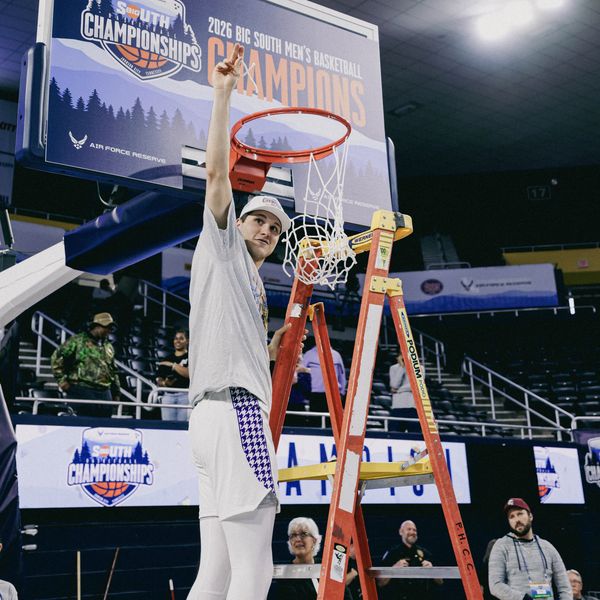 Basketball player celebrating championship victory while cutting down net.