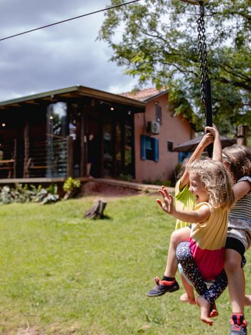 Crianças se divertem em balanço em casa.