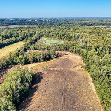 Aerial view of farmland and forest under blue sky.