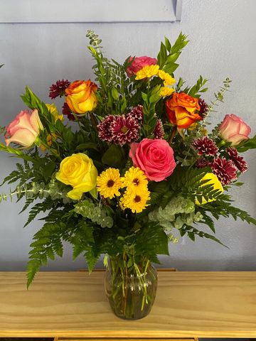 Enjoy a variety of colors with mixed roses and daisies. Displayed in a vase with greenery.