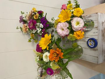 Three colorful flower bouquets in glass vases on a wooden surface.