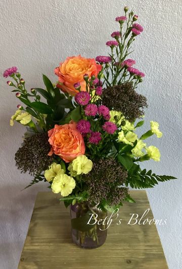 Colorful floral arrangement in a clear vase on a wooden table.