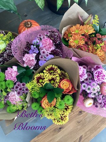 Colorful flower bouquets wrapped in paper on a wooden surface.