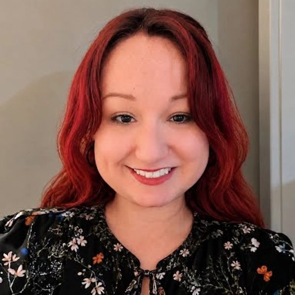 Smiling woman with red hair and floral blouse.