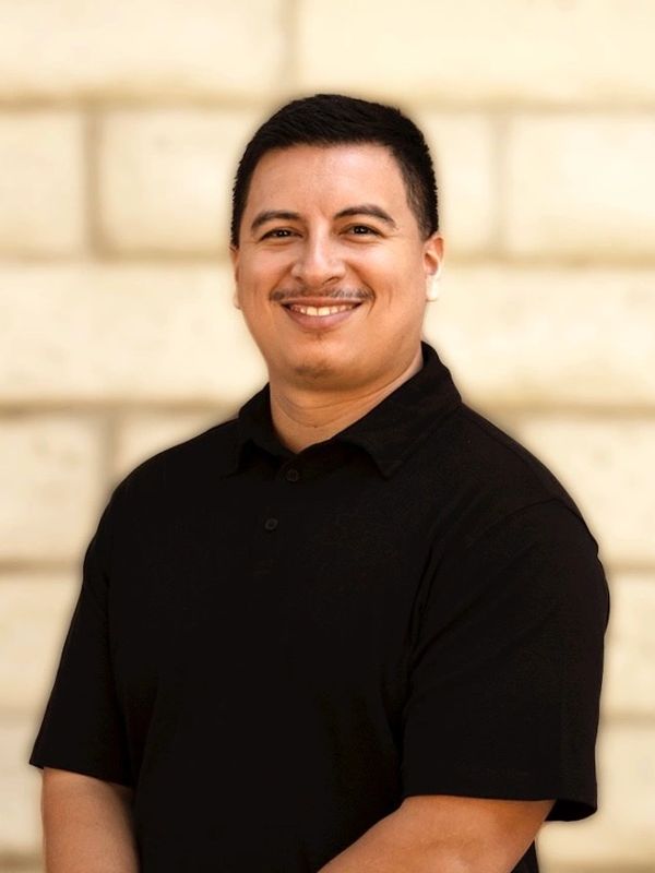 Smiling man in a black polo shirt.