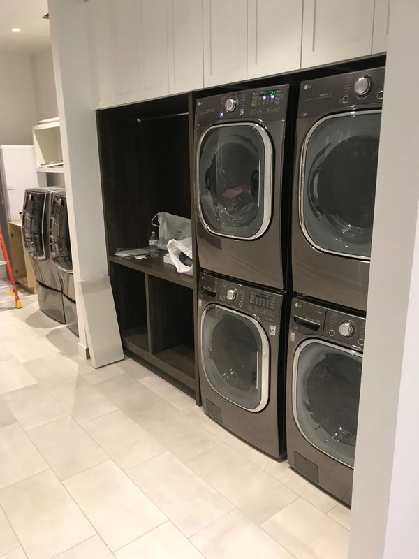 A laundry room with multiple stacked washers and dryers in a modern setting.