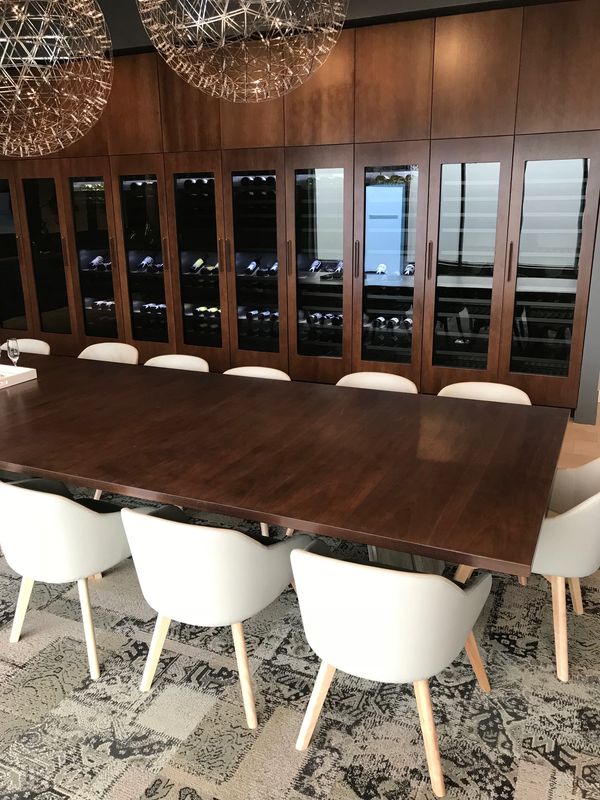 Modern dining room with dark wood table, white chairs, and a wine storage cabinet.