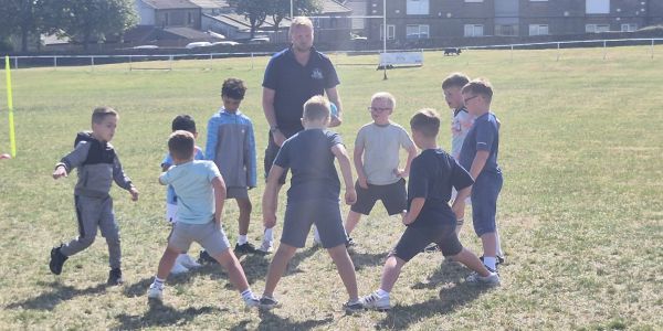 Kids playing soccer with coach on grassy field.