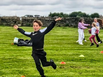 A child joyfully running on grass during outdoor play.