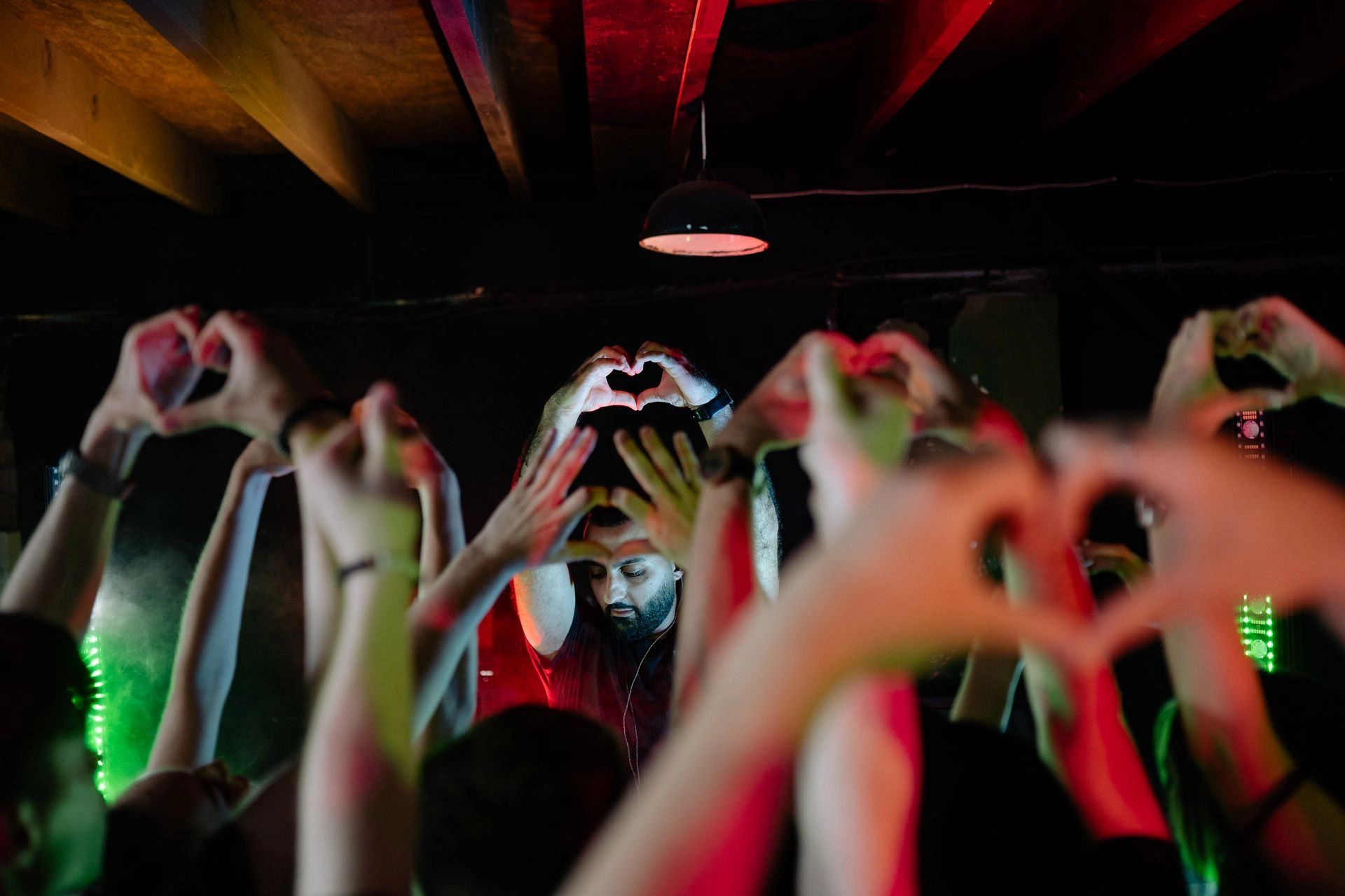 People making heart shapes with their hands at a concert.