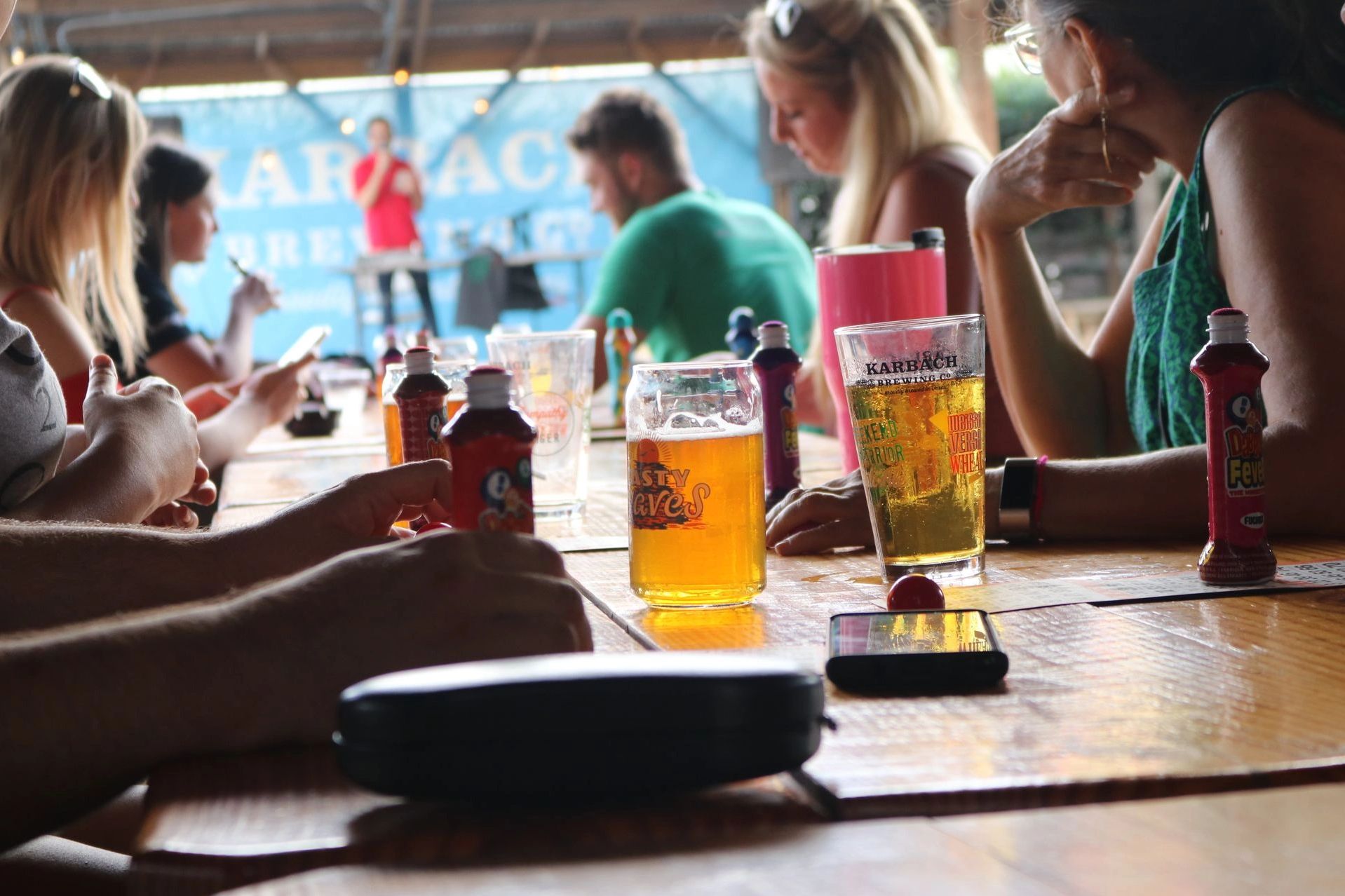 Group enjoying drinks and snacks at a wooden table.