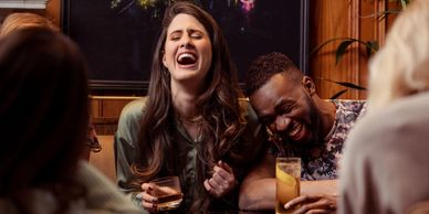 Two friends laughing and enjoying drinks together.