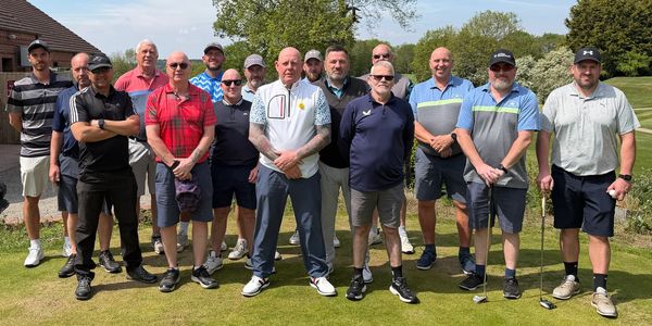 Group of men posing on a golf course on a sunny day.