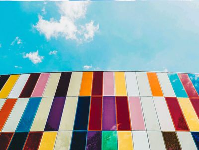 Colorful vertical panels on a curved building against a blue sky.
