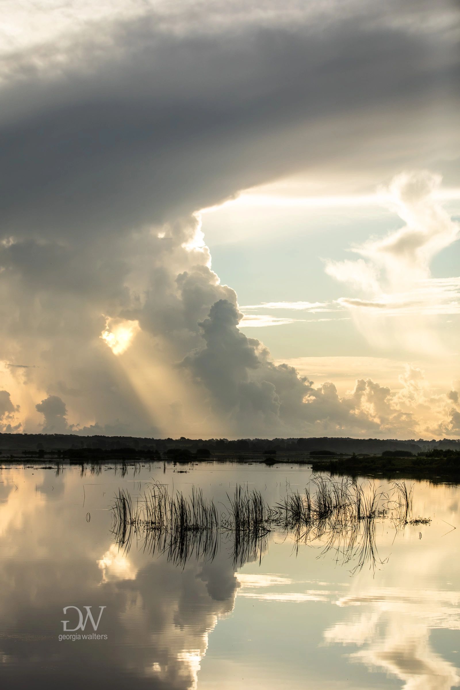 the sun shines down through an opening in a storm cloud