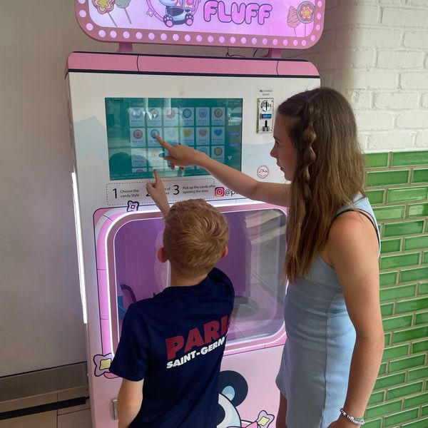 Two young children using a candy floss machine