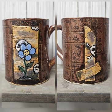 Rustic mug with skull and flower artwork on opposite sides.