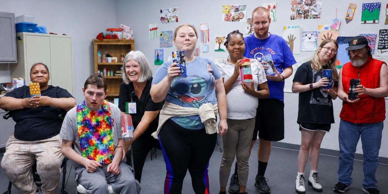Diverse group holding handmade crafts and smiling.