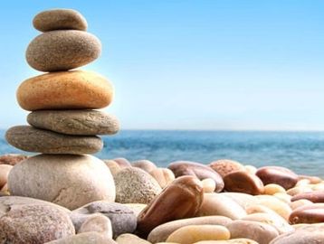 Stacked stones balanced on a rocky beach with the sea and sky in the background.